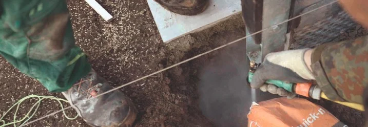 Person betoniert einen Pfosten ein